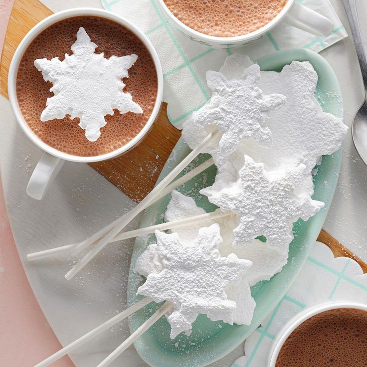 two cups of hot chocolate and marshmallows on a plate