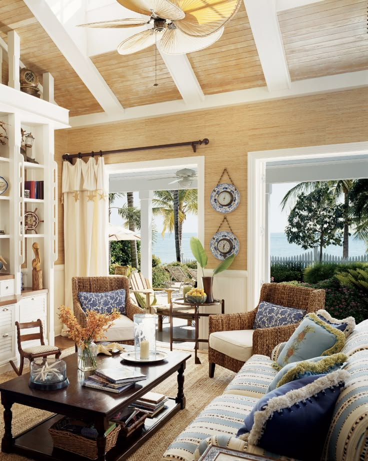 a living room filled with lots of furniture next to a large open window overlooking the ocean