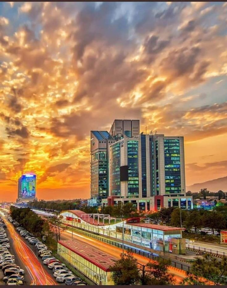 the sun is setting over a city with tall buildings and cars on the road below