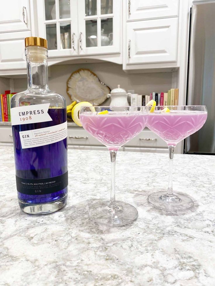 two glasses filled with liquid sitting on top of a counter next to a bottle of liquor