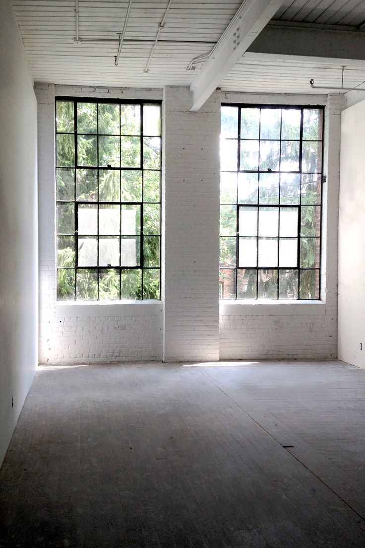 an empty room with two large windows in it