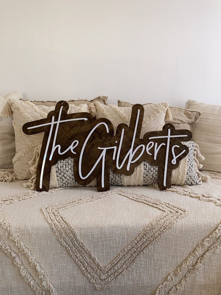 two decorative pillows sitting on top of a bed with the word the gliders spelled in cursive letters