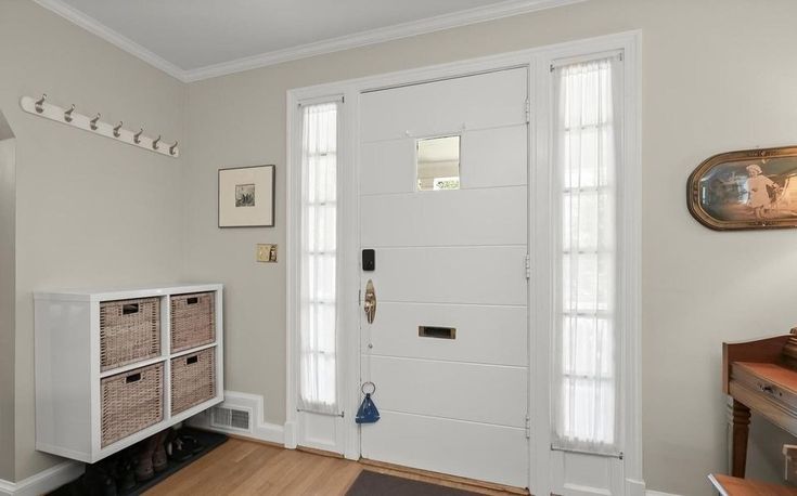 an entryway with white doors and baskets on the floor next to a wooden table