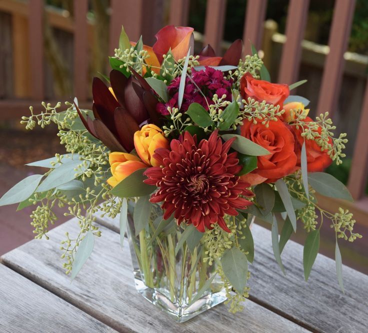 a vase filled with lots of flowers on top of a wooden table