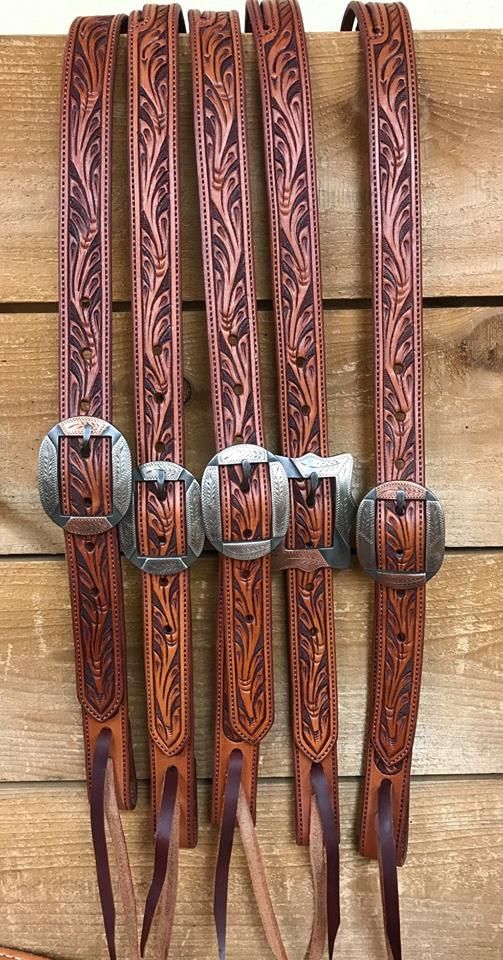 four different types of leather belts hanging on a wooden wall