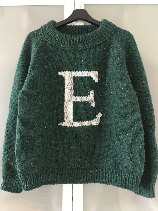 a green sweater with the letter e on it