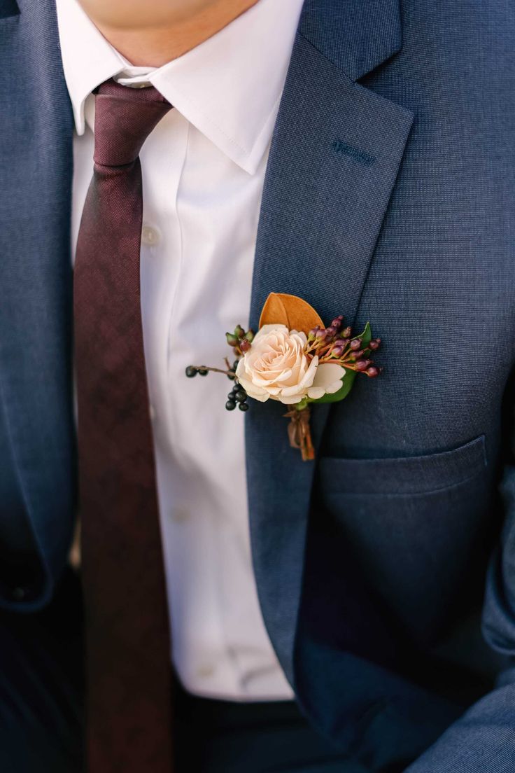 a man wearing a suit and tie with a boutonniere on his lapel