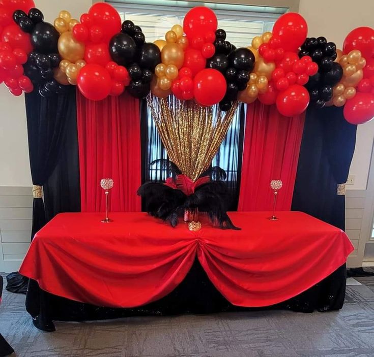 a red table with black and gold balloons on it