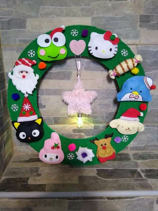 a christmas wreath decorated with stuffed animals and other holiday related items is hanging on the wall