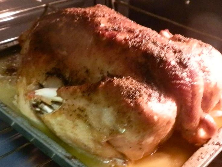 a roasted chicken sitting in an oven on top of a pan with gravy