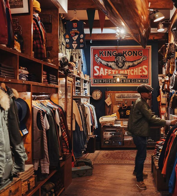 a man standing inside of a store filled with clothing