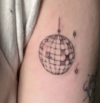 a woman's arm with a tattoo on it that looks like a disco ball