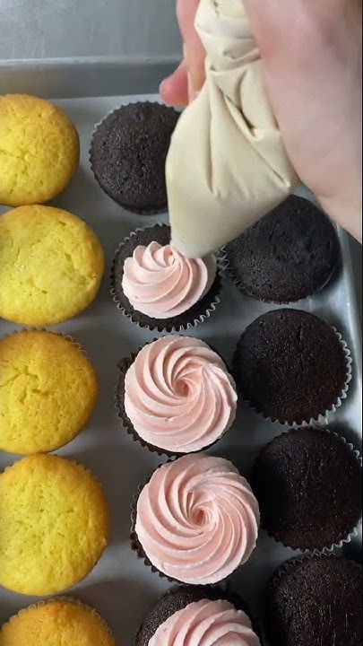 someone is decorating cupcakes with pink frosting