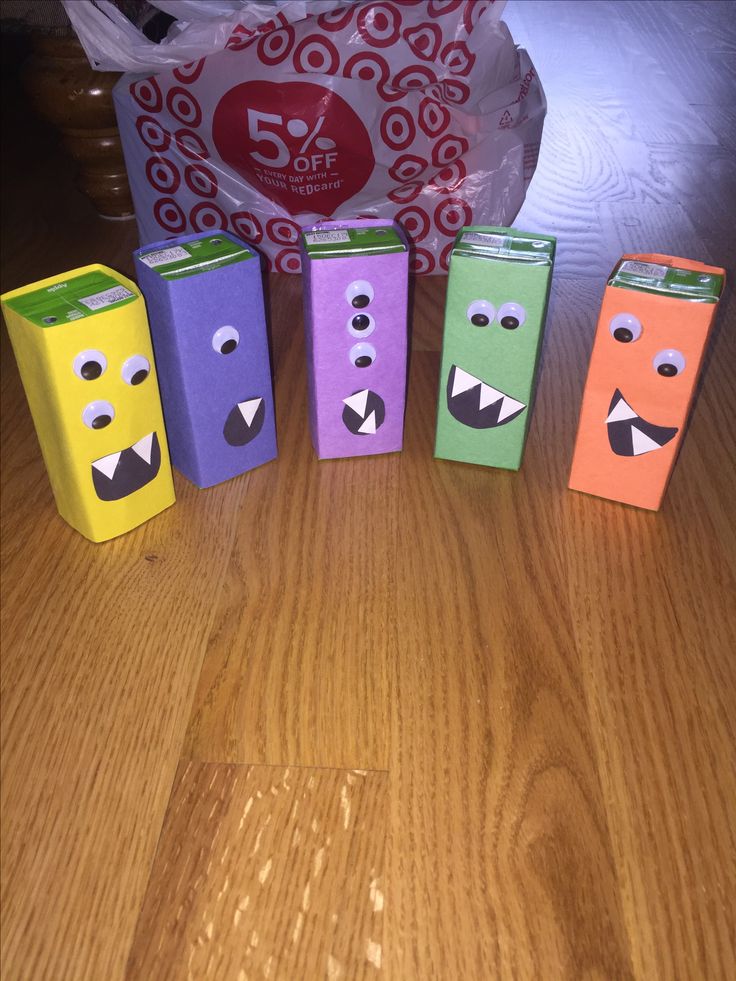 four boxes with faces painted on them sitting on a wooden table next to a bag