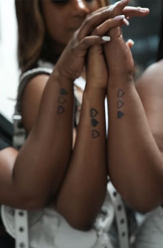 a woman with two tattoos on her arms and both hands folded up in front of her face