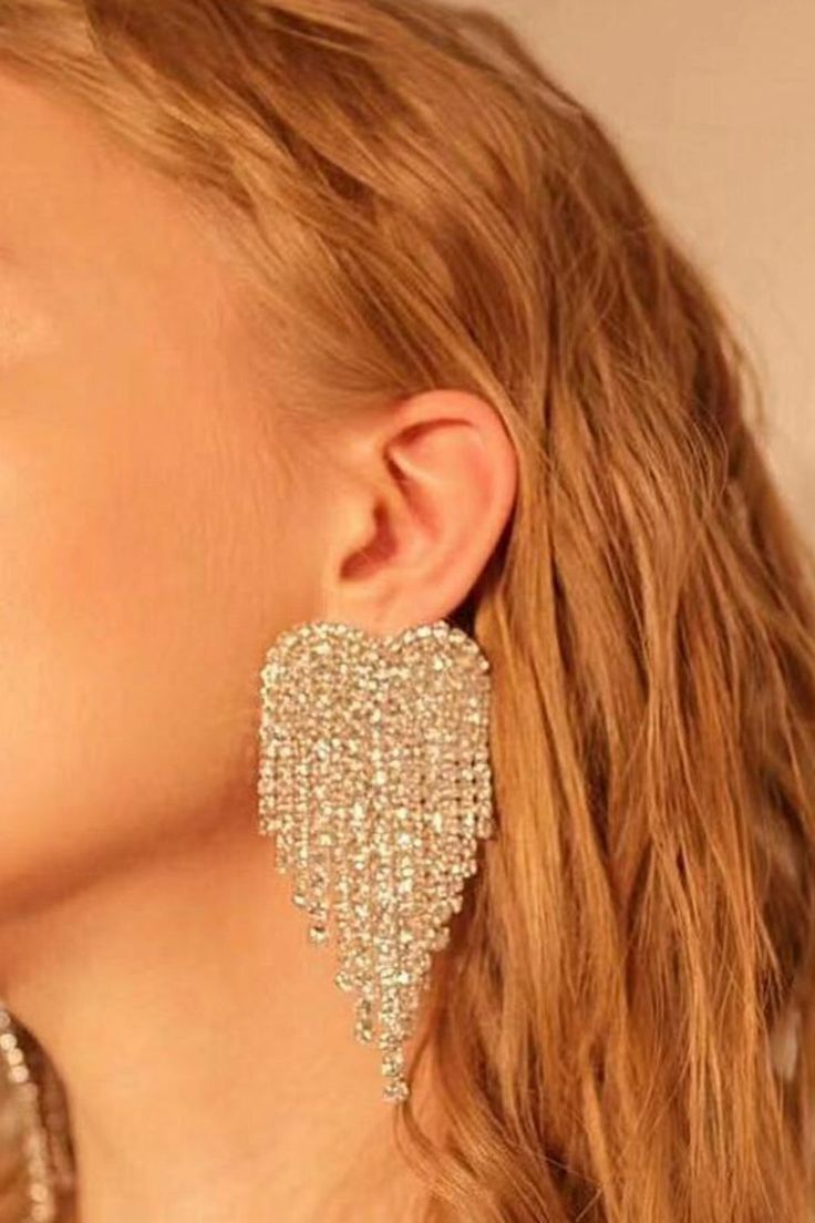 Shiny Rhinestone Long Charm Dangle Heart Shaped Crystal Tassel Earring You'll be the favorite girl in the room with our long, dangling earrings that sparkle and shine. The perfect accessory for any outfit, these heart shaped Rhinestone Earrings are a true score. Wear them for casual day, for a night out with the girls, or dress them up for a formal occasion. Whether you've got a dressy event coming up or just want to add a little bling to your outfit, these statement dangle earrings are sure to Trendy Dangle Heart Earrings For Wedding, Trendy Heart Dangle Earrings For Wedding, Valentine's Day Gold Crystal Earrings, Gold Crystal Heart Earrings, Gold Heart Shaped Crystal Earrings, Glamorous Crystal Heart Earrings, Single Earring For Valentine's Day Party, Trendy Metal Heart Earrings For Party, Crystal Heart Earrings With Rhinestones