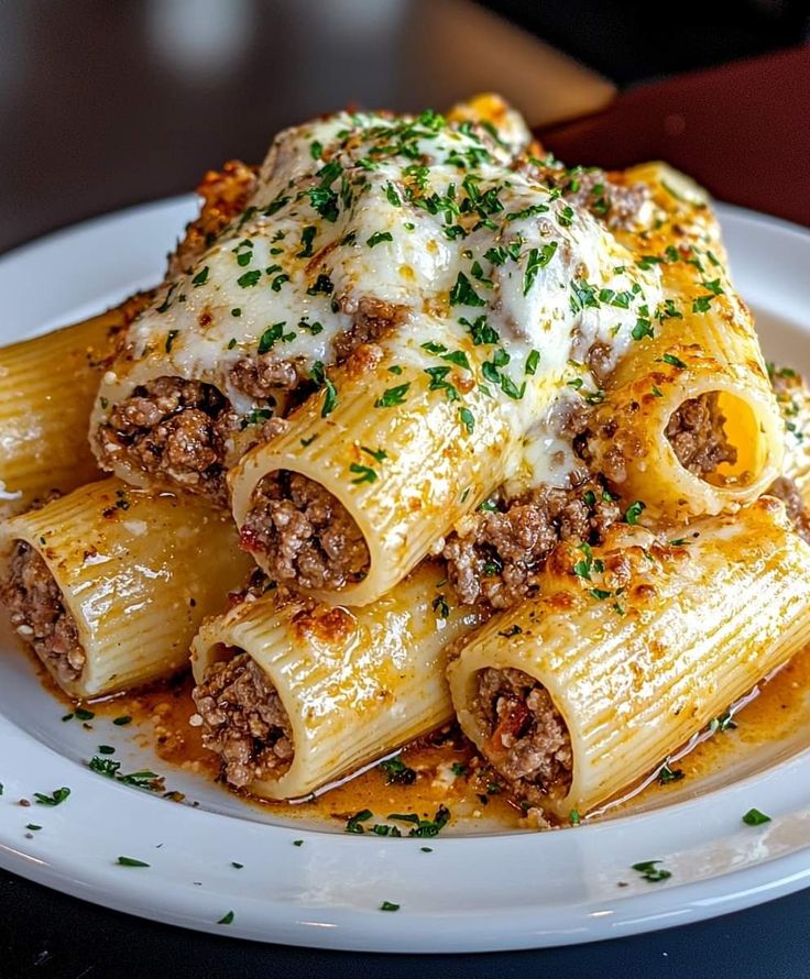 a white plate topped with pasta covered in meat and sauces on top of it