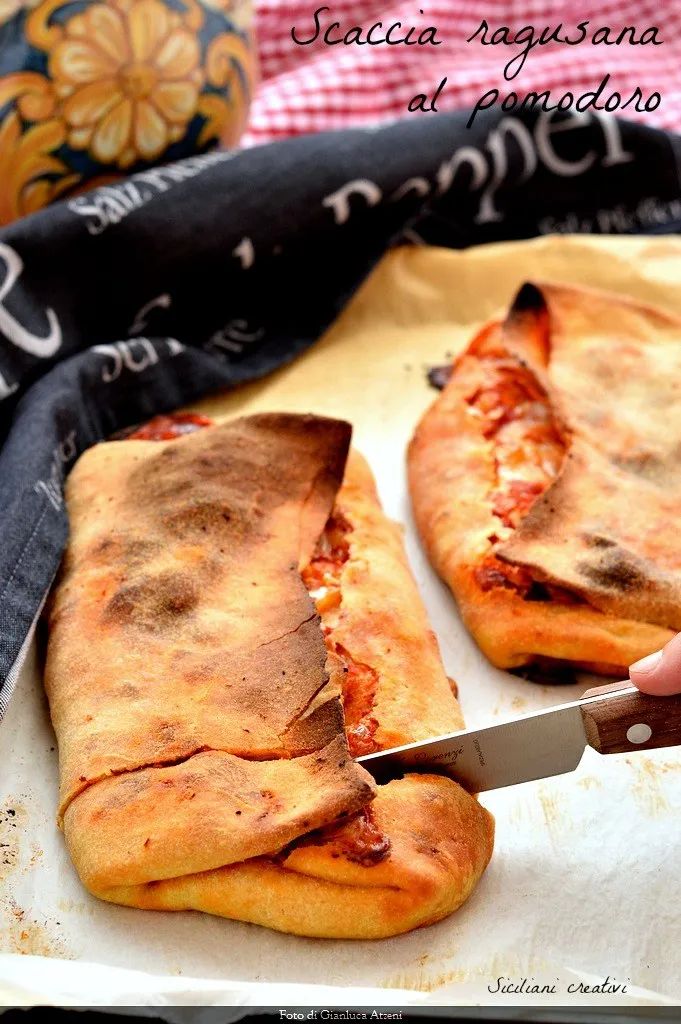 someone cutting up some pizza on top of a sheet of parchment paper with a knife