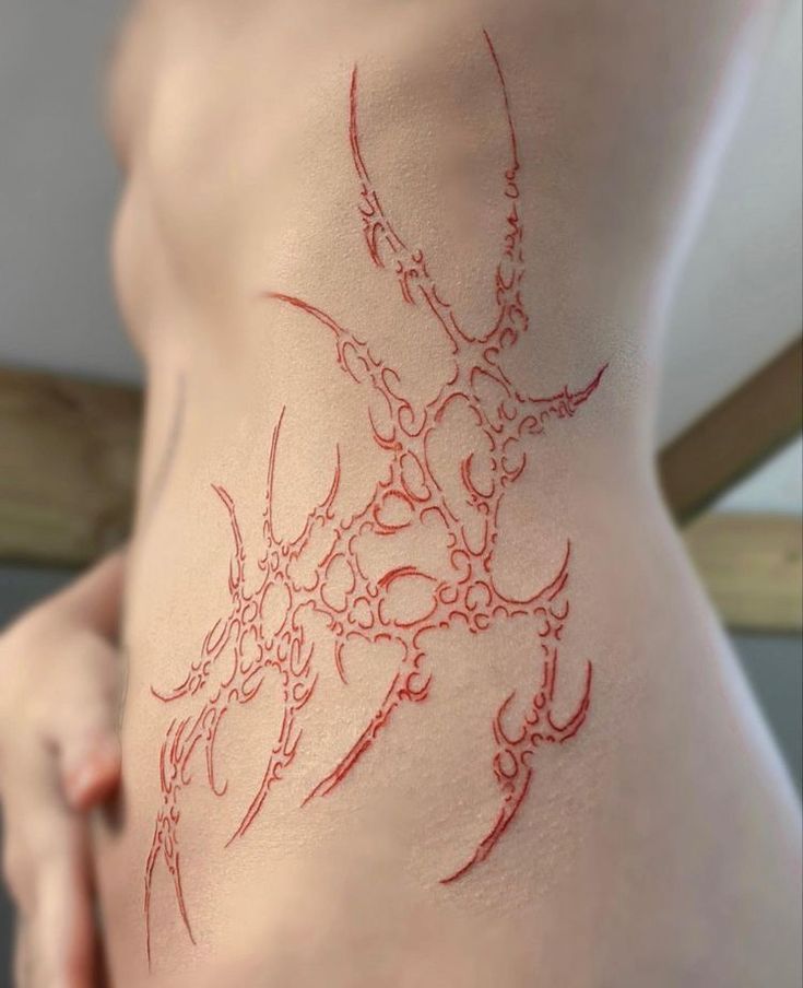 a close up of a person's stomach with red ink on the side of her body