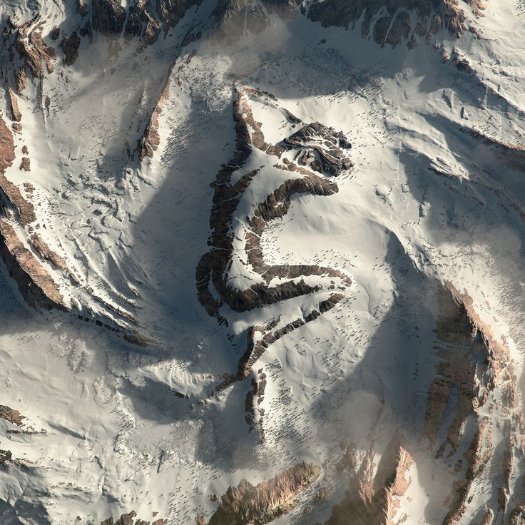 an aerial view of snow covered mountains and valleys