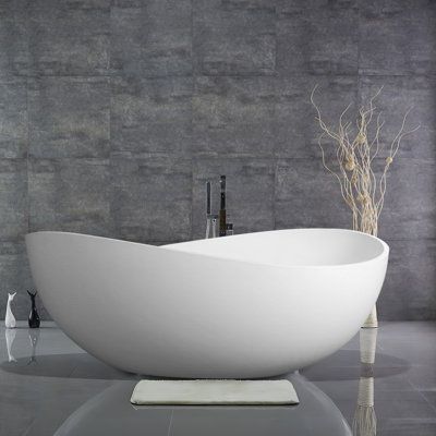 a large white bathtub sitting on top of a table next to a vase with flowers