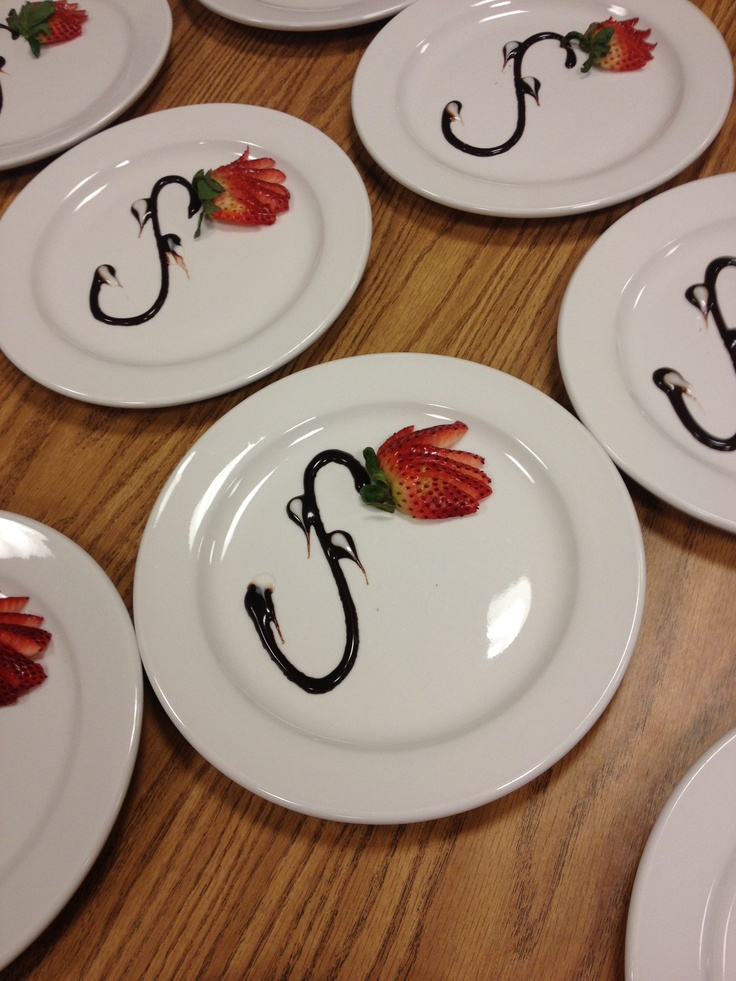 white plates with black letters and strawberries on them sitting on a wooden table top