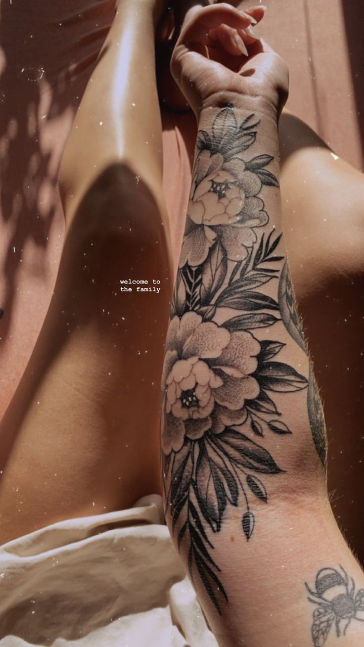 a woman's arm with flowers on it and her hand resting on the leg