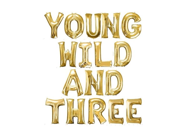 the words young wild and three are gold foil balloons