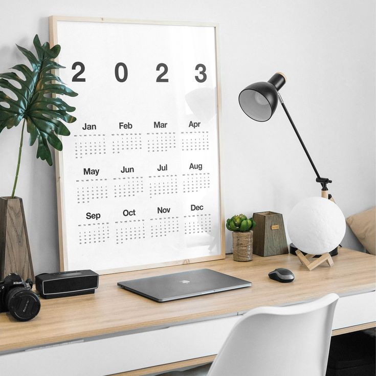 a desk with a laptop, phone and other items on it next to a plant