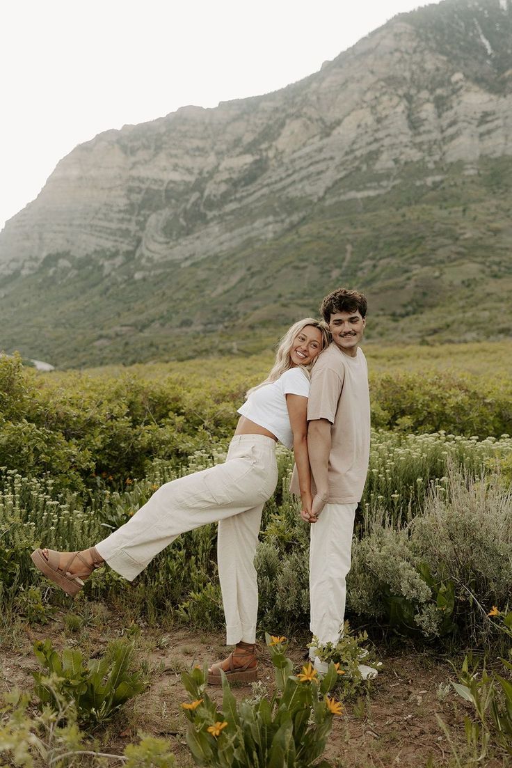 a man and woman are posing for a photo in the mountains with their arms around each other