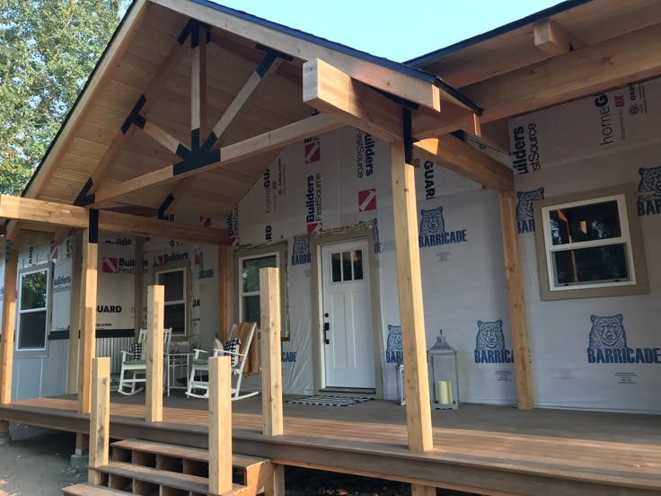 a house under construction with the front porch covered in siding and wood beams attached to the roof