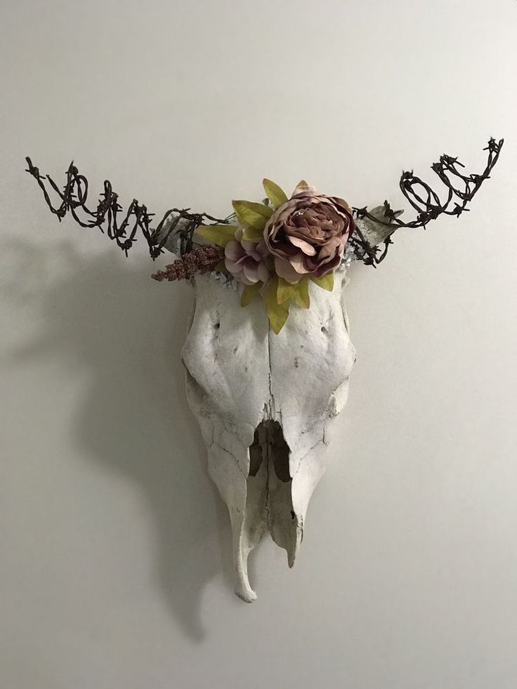 an animal skull with flowers on it's head and barbed wire around its neck