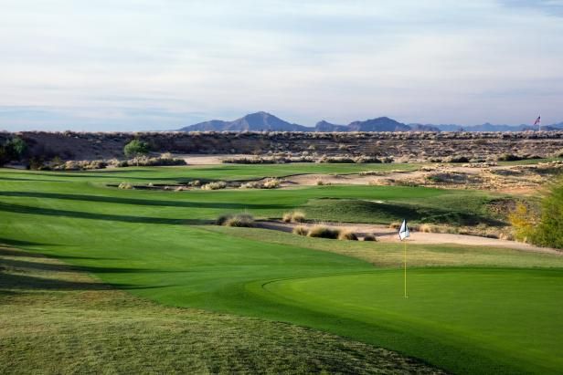 a golf course in the desert with mountains in the background