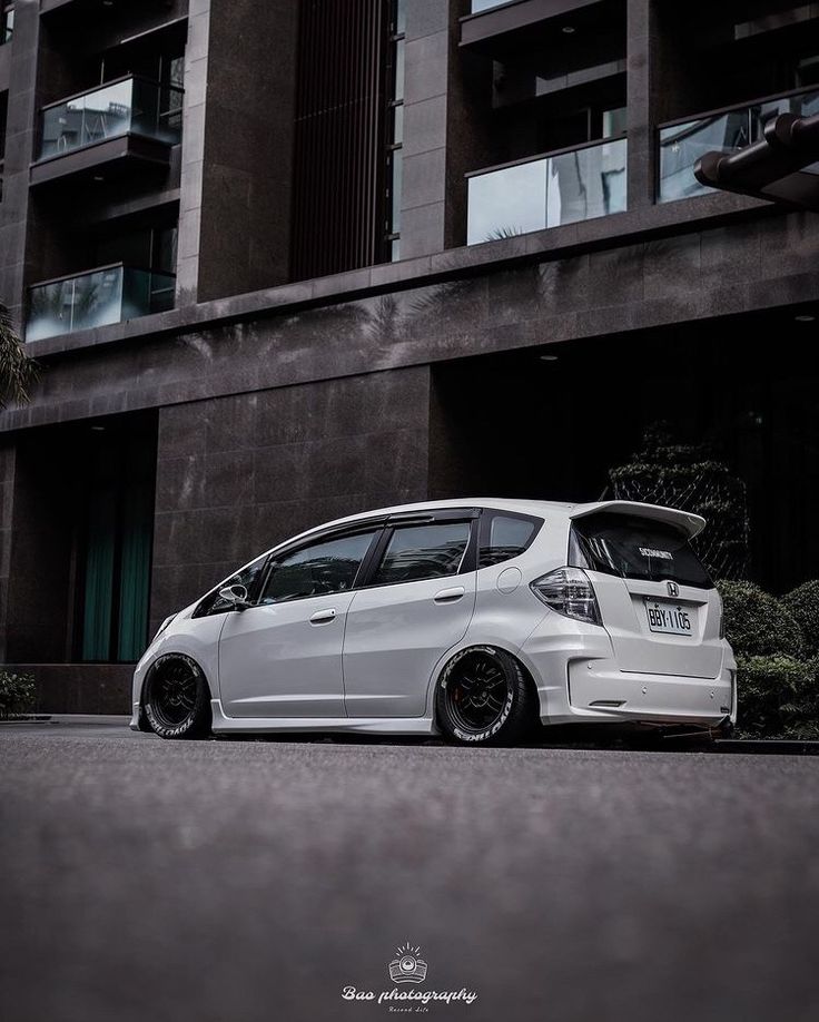 a white car parked in front of a tall building