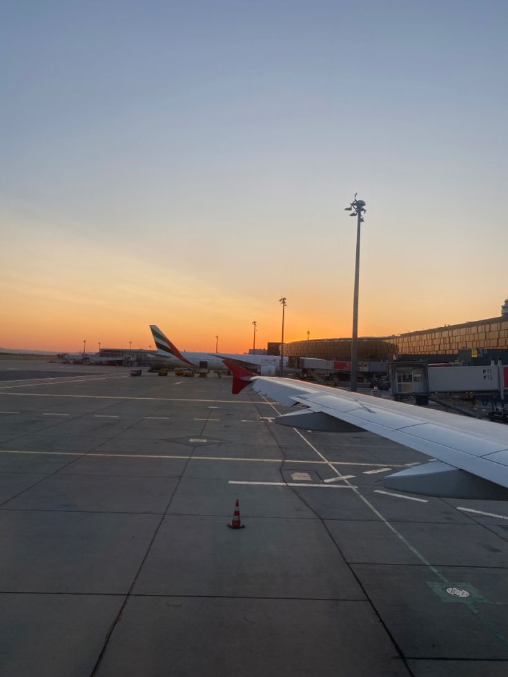 an airplane is parked on the runway at sunset