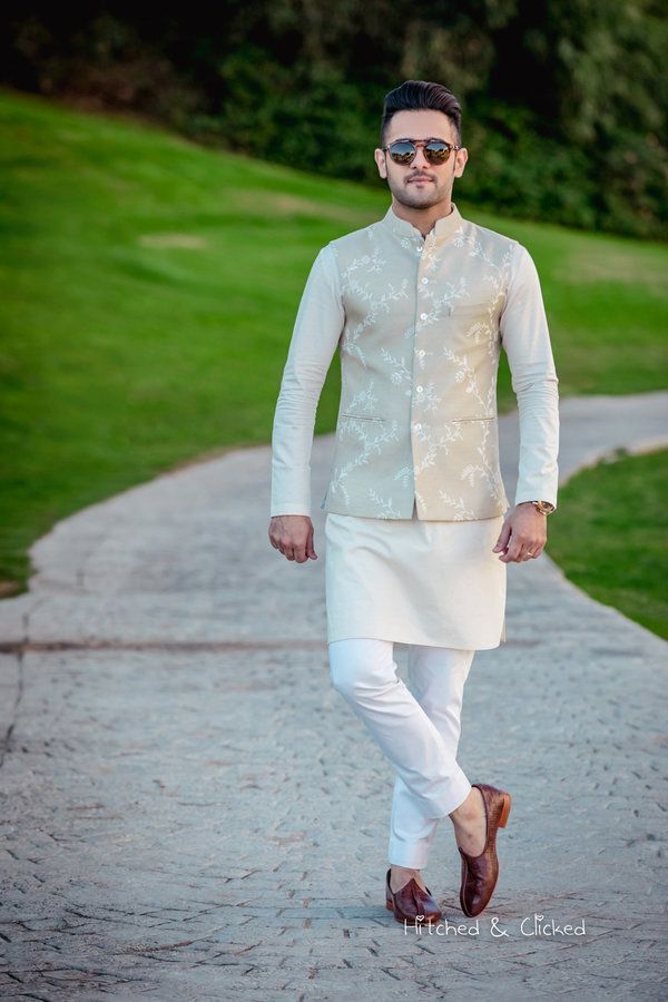 a man in a white outfit walking down a sidewalk with his hand on his hip