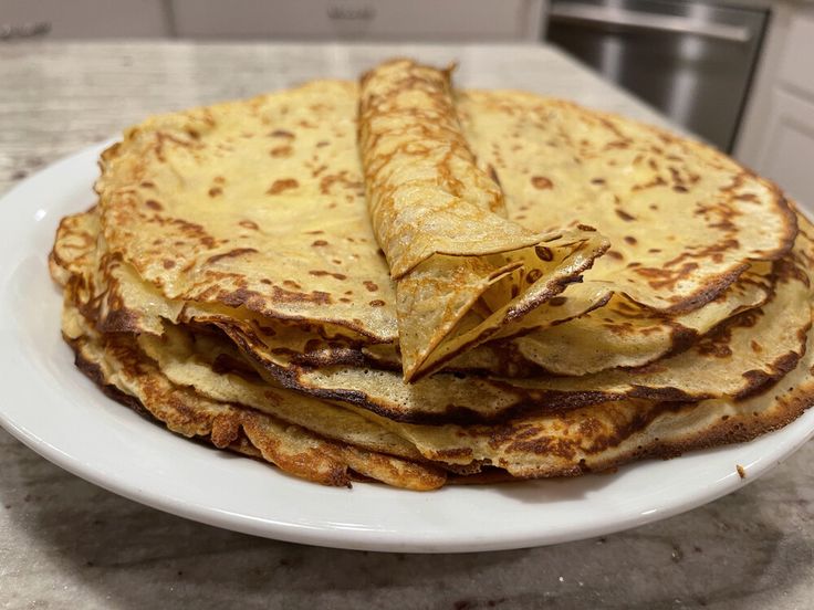 a stack of tortillas sitting on top of a white plate in a kitchen