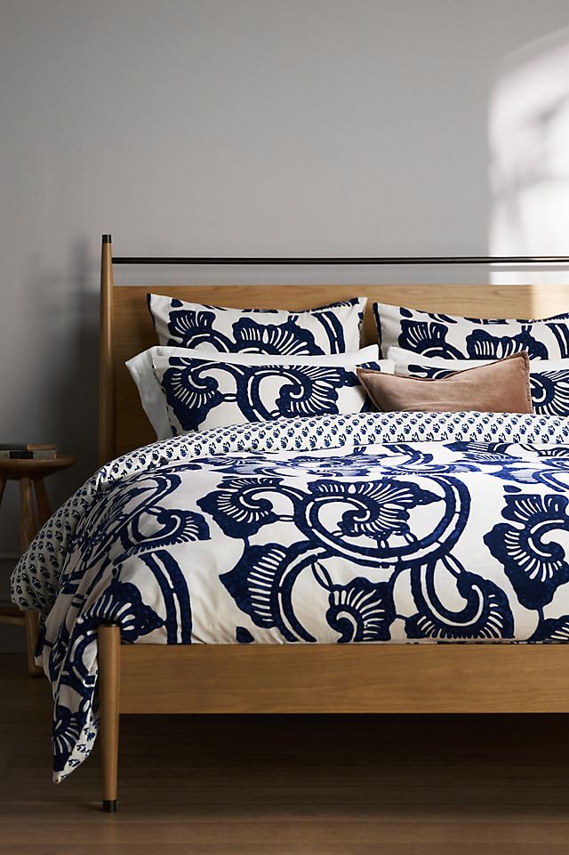 a bed with blue and white bedspread, pillows and pillow cases on it