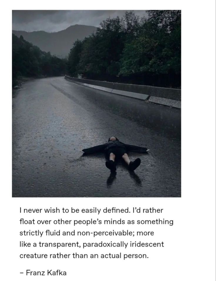 a person laying on the ground in the middle of a road with an umbrella over their head