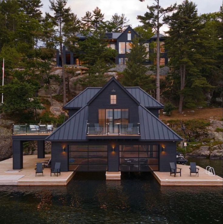 a house on the water with a dock in front of it and lots of windows