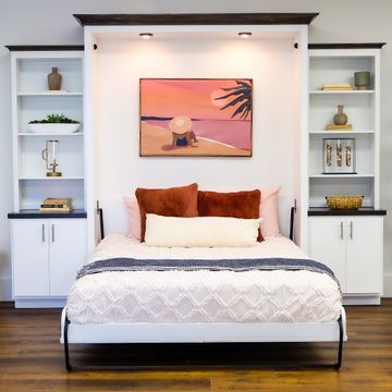 a bed sitting in the middle of a bedroom next to a wall mounted book shelf