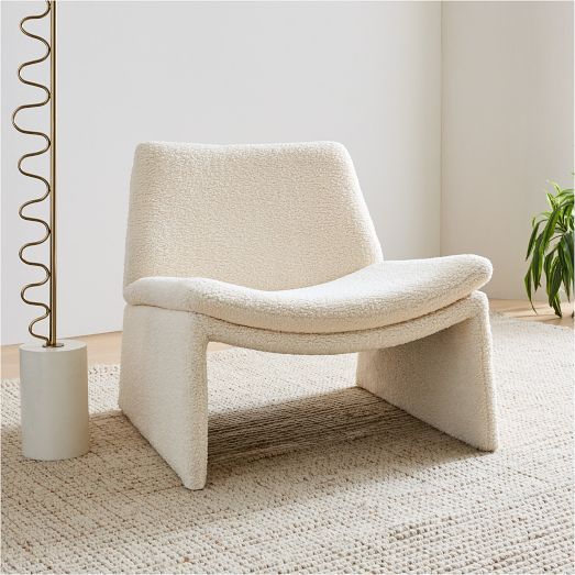 a white chair sitting on top of a rug next to a potted plant