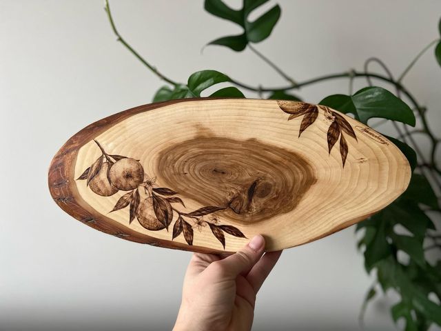 a hand holding a wooden bowl with leaves on it