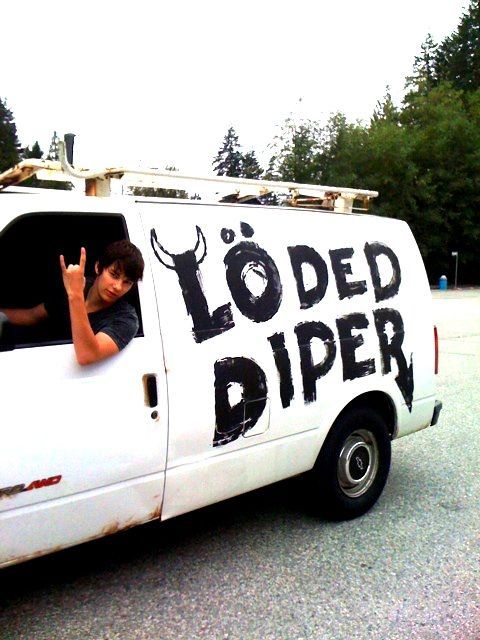 a young boy sitting in the back of a white van with black writing on it