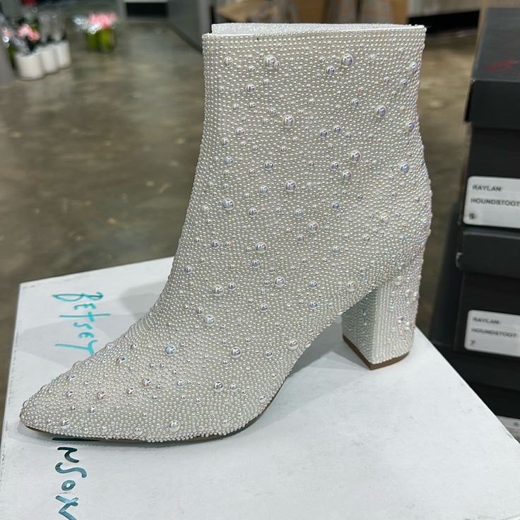 The Cady Is A Disco-Ready Bootie That Will Take Any Outfit You Wear To The Next Level. These Ankle Boots Feature A Pointed Toe And A Study, Block Heel And Are Fully Decked Out With Pearl Rhinestones. Glitz And Glam Have Never Looked Better. Pearl Embellished Booties Side Zipper Closure Textile Lining Betsey Blue Sole 3.5 Inch Heel Height 5.5 Inch Shaft Height Formal Rhinestone Boots For Spring, White Party Boots With Reinforced Heel, White Closed Toe Party Boots, White Closed-toe Party Boots, White Rhinestone Boots With Round Toe, White Rhinestone Boots For Spring, White Synthetic Boots For Formal Occasions, White Round Toe Boots For Evening, White Almond Toe Boots For Party