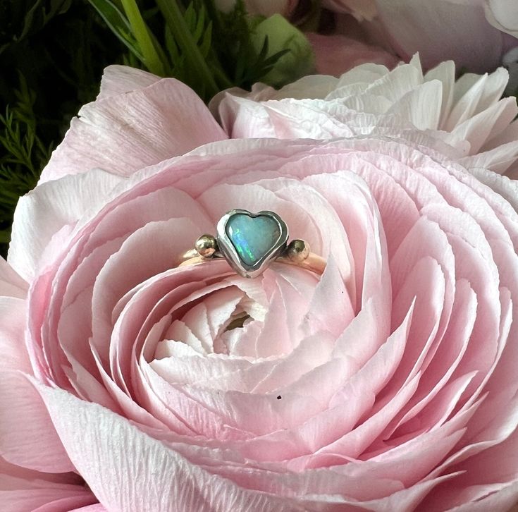 This darling one of a kind ring features a beautiful Australian opal heart which I set in a chunky handmade sterling silver bezel. It sits perched atop a heavy fun round 14k yellow antique reclaimed wedding band, which has an engraving of 9-15-56 along with initials in cursive. I melted two little gold pebbles from scrap and flanked the stone with them. I oxidized the silver bezel to a darker black finish, to contrast with the stone and the yellow gold. One Of A Kind Heart Jewelry For Anniversary, Heirloom Opal Ring With Bezel Setting For Anniversary, Unique Opal Ring With Bezel Setting For Anniversary, Opal Ring With Bezel Setting Gift, Oval Cabochon Opal Ring With Bezel Setting As Gift, Opal Jewelry With Bezel Setting For Gift, Adjustable Opal Ring With Bezel Setting, One-of-a-kind Opal Jewelry For Anniversary, Sterling Silver Opal Ring With Bezel Setting