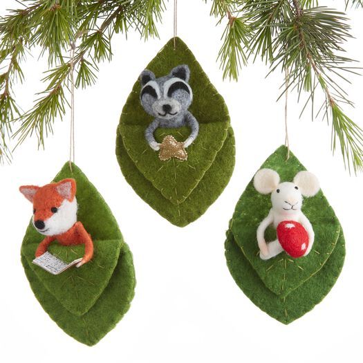 three ornaments hanging from a christmas tree decorated with green leaves and red animals on them