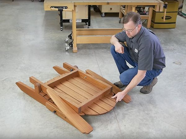 a man working on a wooden boat in a shop with other woodworking tools around him