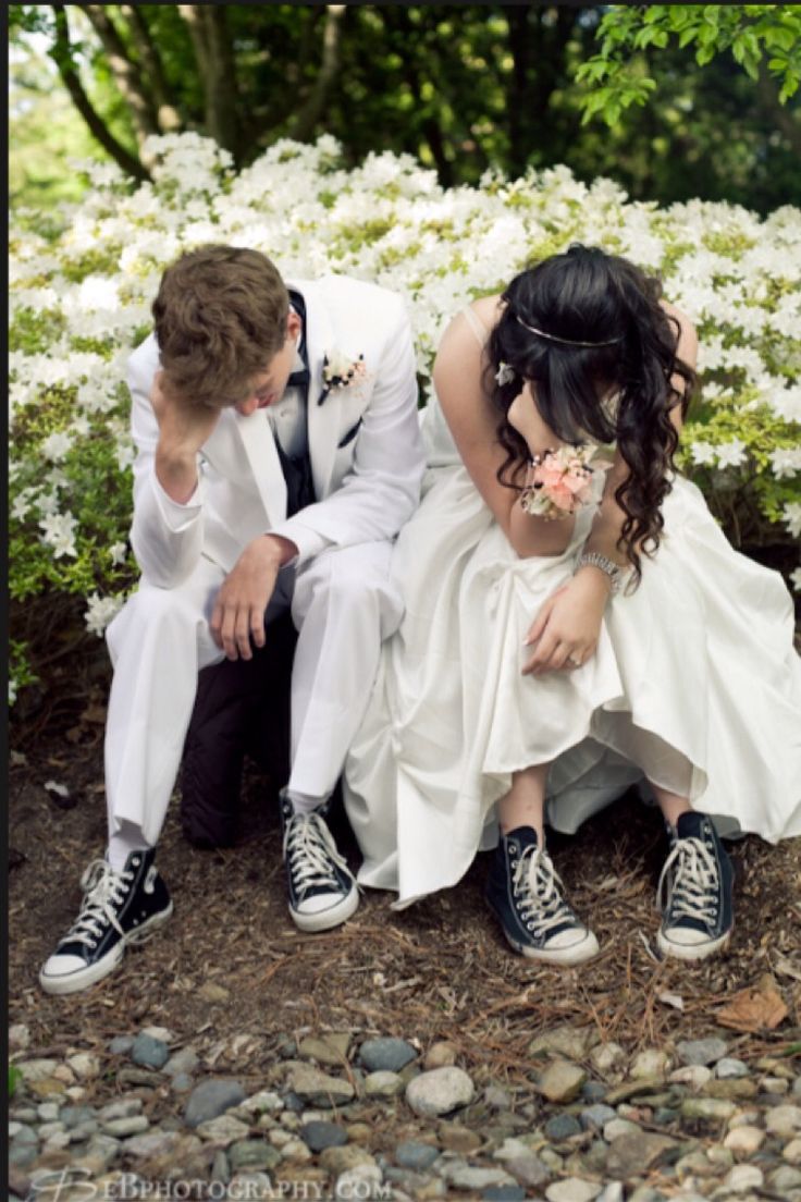 a man and woman sitting next to each other in front of white flowers on the ground