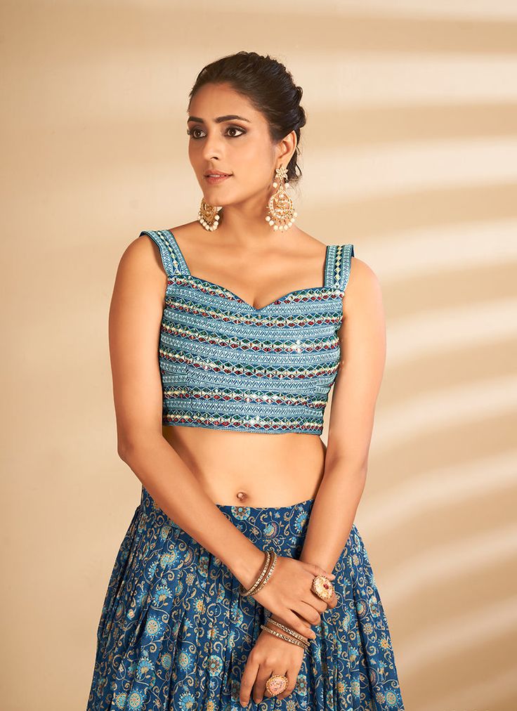 Blue Multi Embroidered Traditional Lehenga Choli will make you look like a diva with its traditional style and beautiful embroidery annotated perfectly with zari, resham thread and badla mirror work on its art silk choli top paired with multicoloured digital printed art silk lehenga. The beauty part of this lehenga is its minimalist soft net latkan embellished dupatta. Style this pretty attire on any wedding or festive party with heels and jewellery to look stunningly beautiful from the rest of